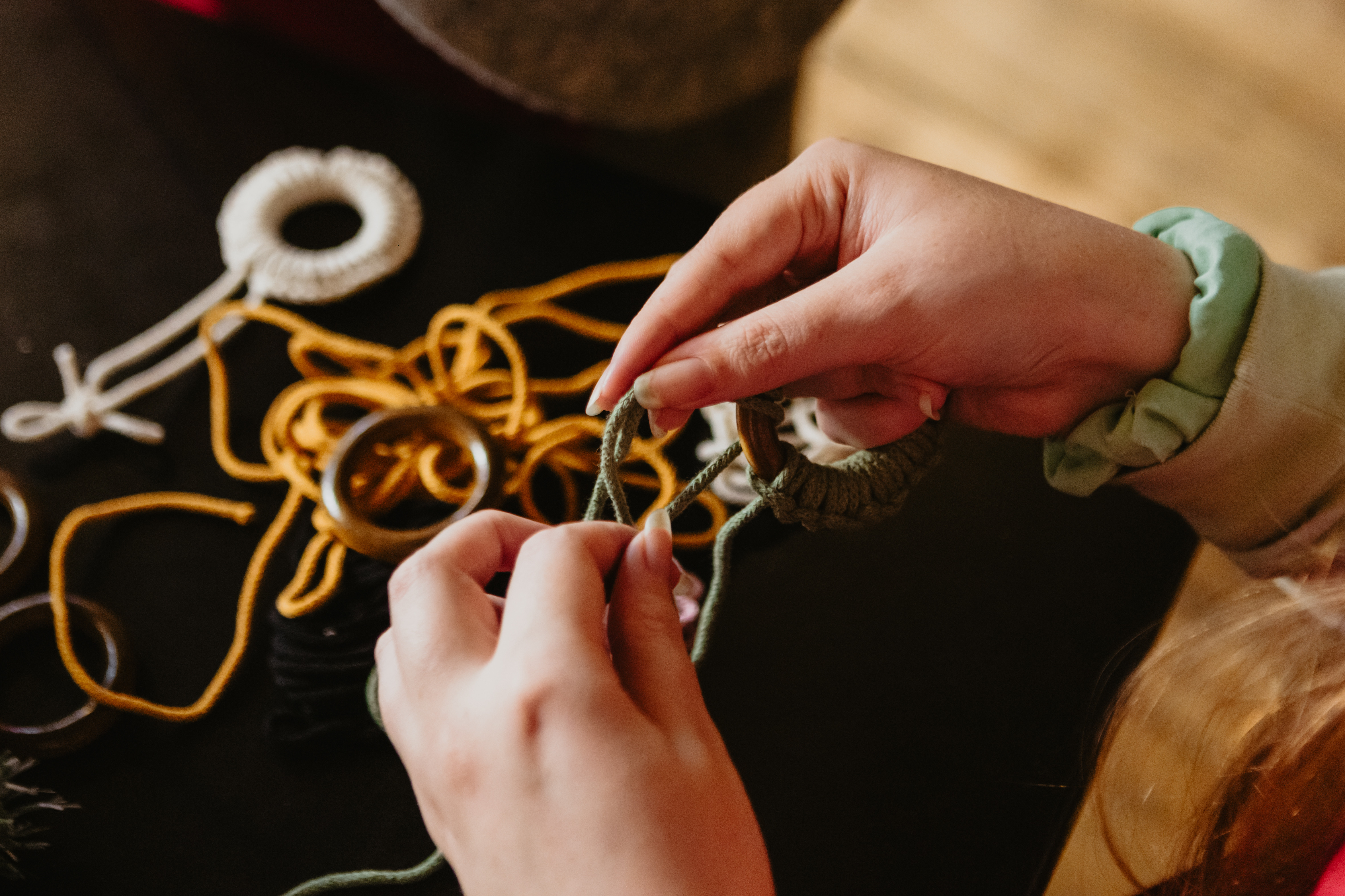 Close up of hands making macrame from a craft kit